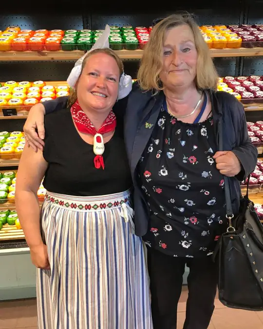 Two women in a cheese shop, one wearing traditional Volendam dress